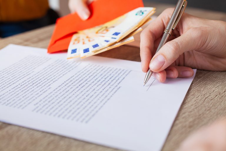main qui ecrit une lettre de motivation sur un bureau en bois, elle tient un stylo plume