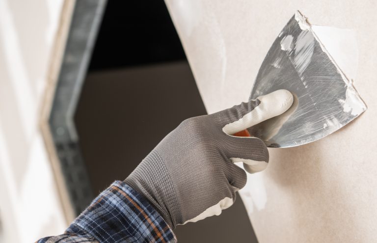 spatule qui étale de l'enduit sur le mur